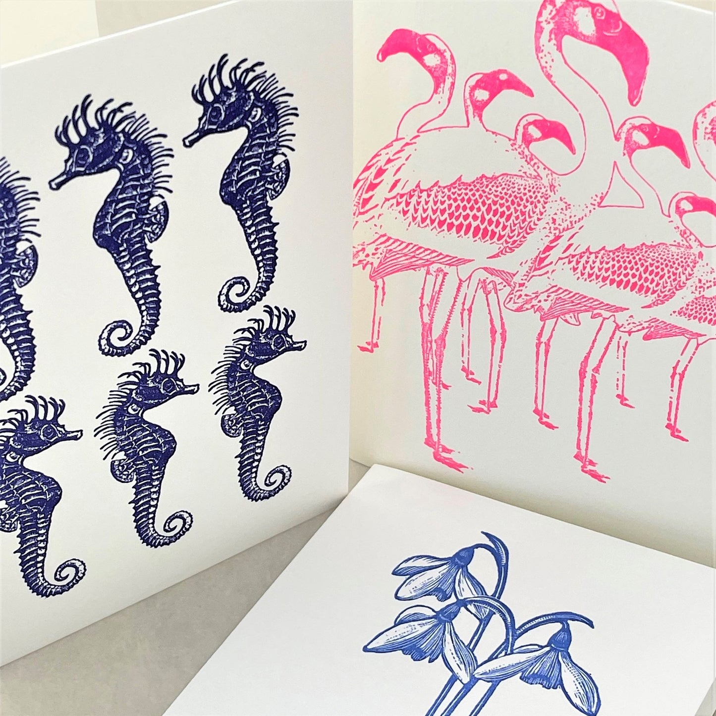 small greetings card with pink flamingos alongside card with seahorses and snowdrops