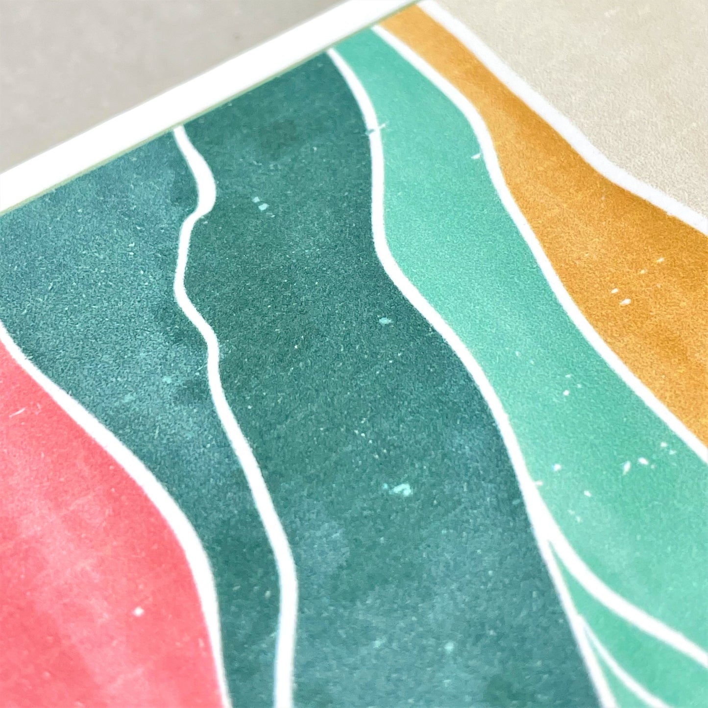 greetings card of a pink sun in the sky over a desert, close up of the card