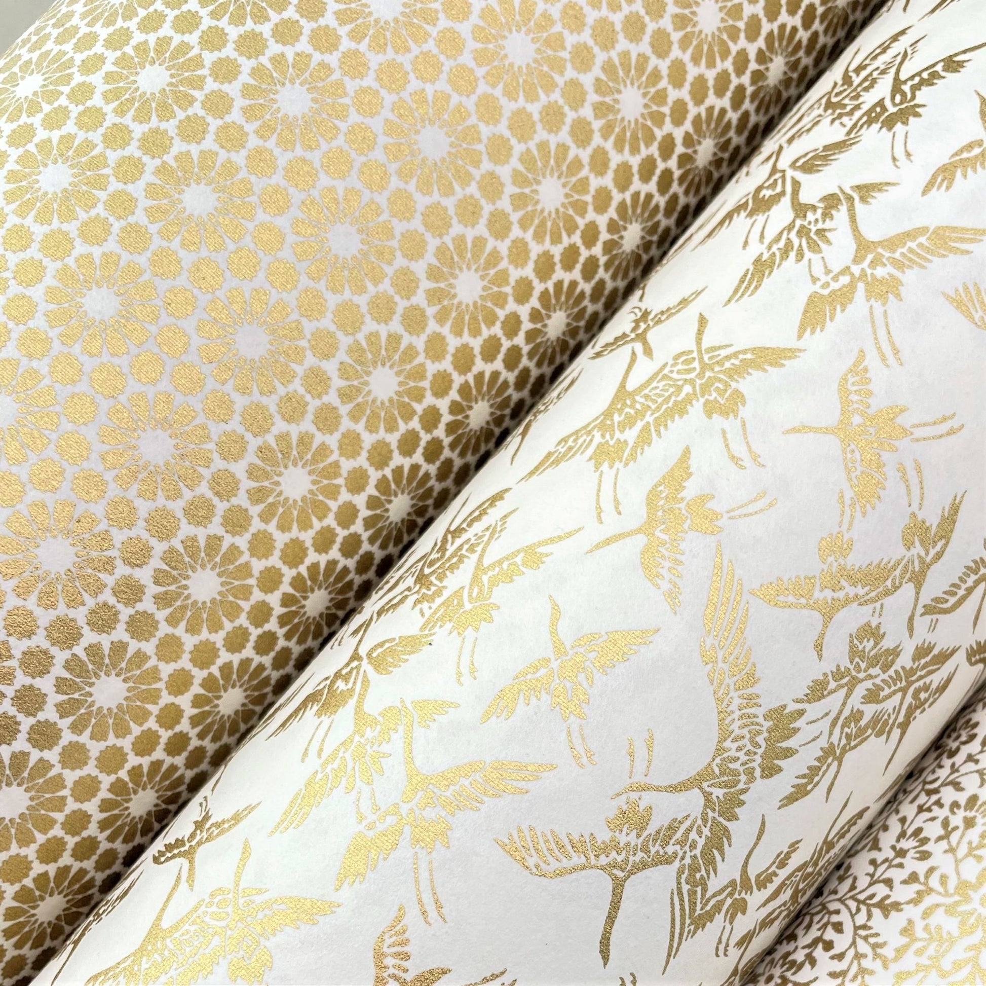 japanese silk-screen handmade paper showing gold repeat chrysanthemum flower motif repeat, lifestyle shot with other gold papers