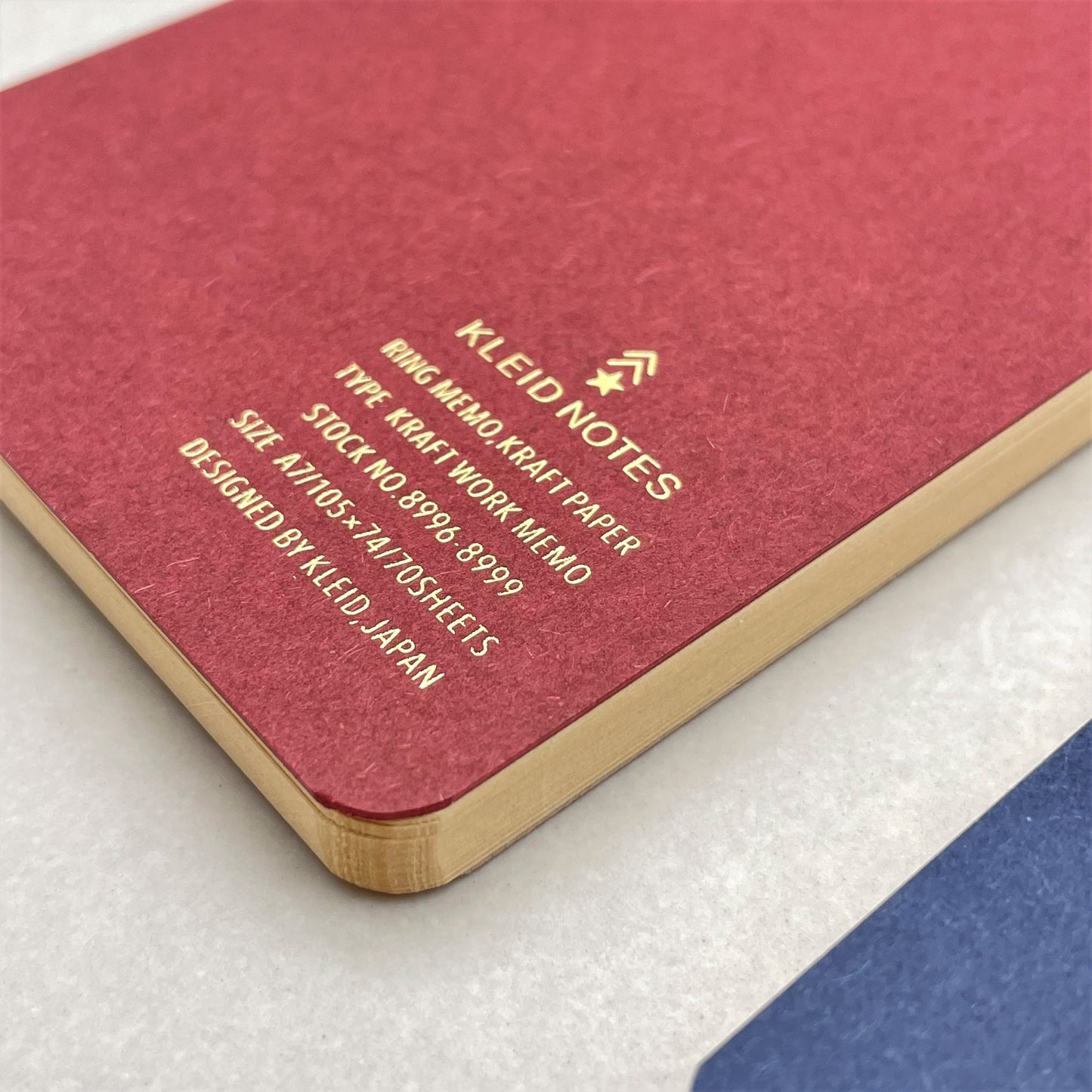 A7 memo ring-bound notepad, cover is plain burgundy with rose-gold dual rings, close-up