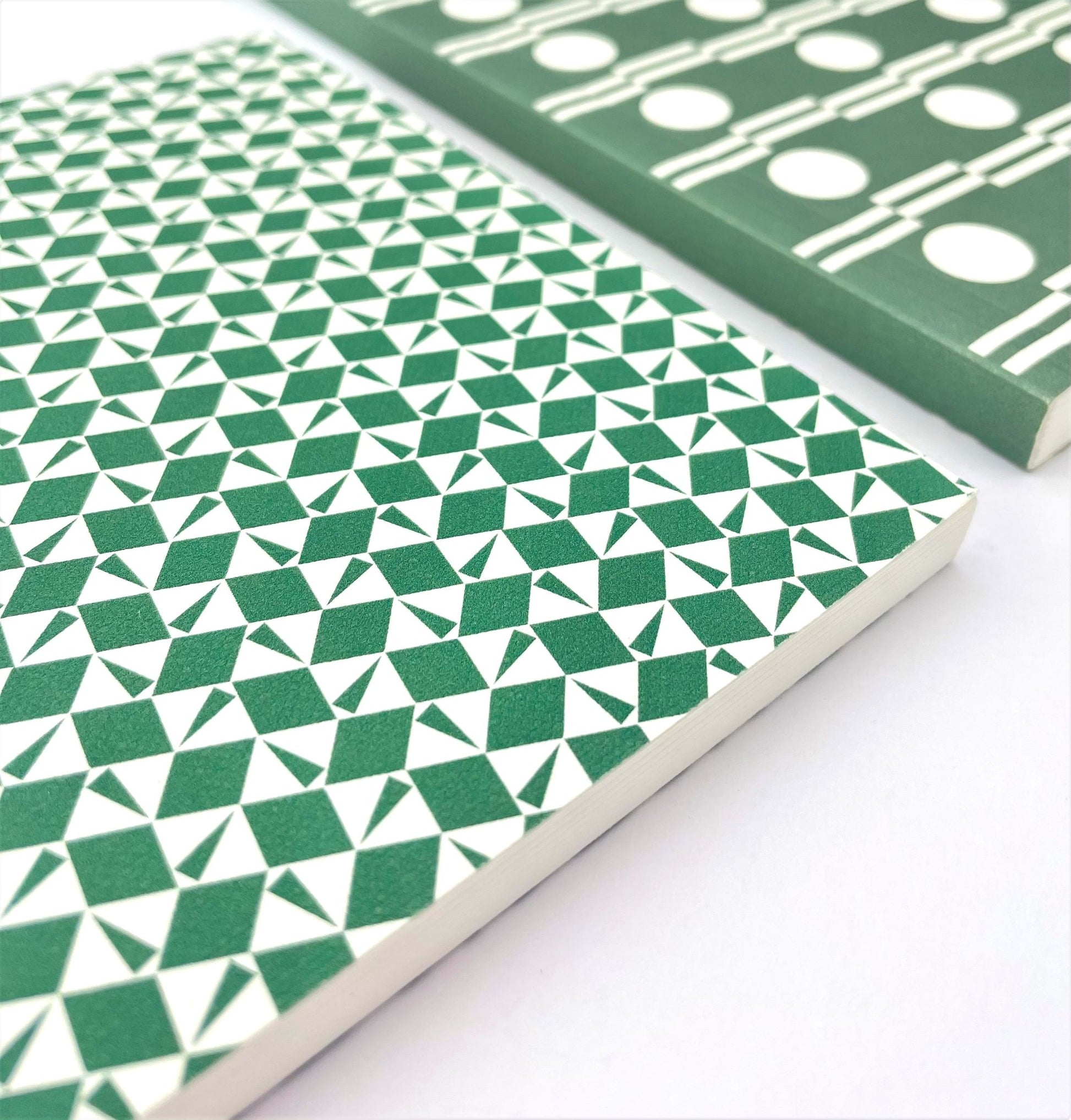 A5 softback notebook with geometric emerald green and white repeat diamond and triangles patterned cover. Dotted inner pages, close-up