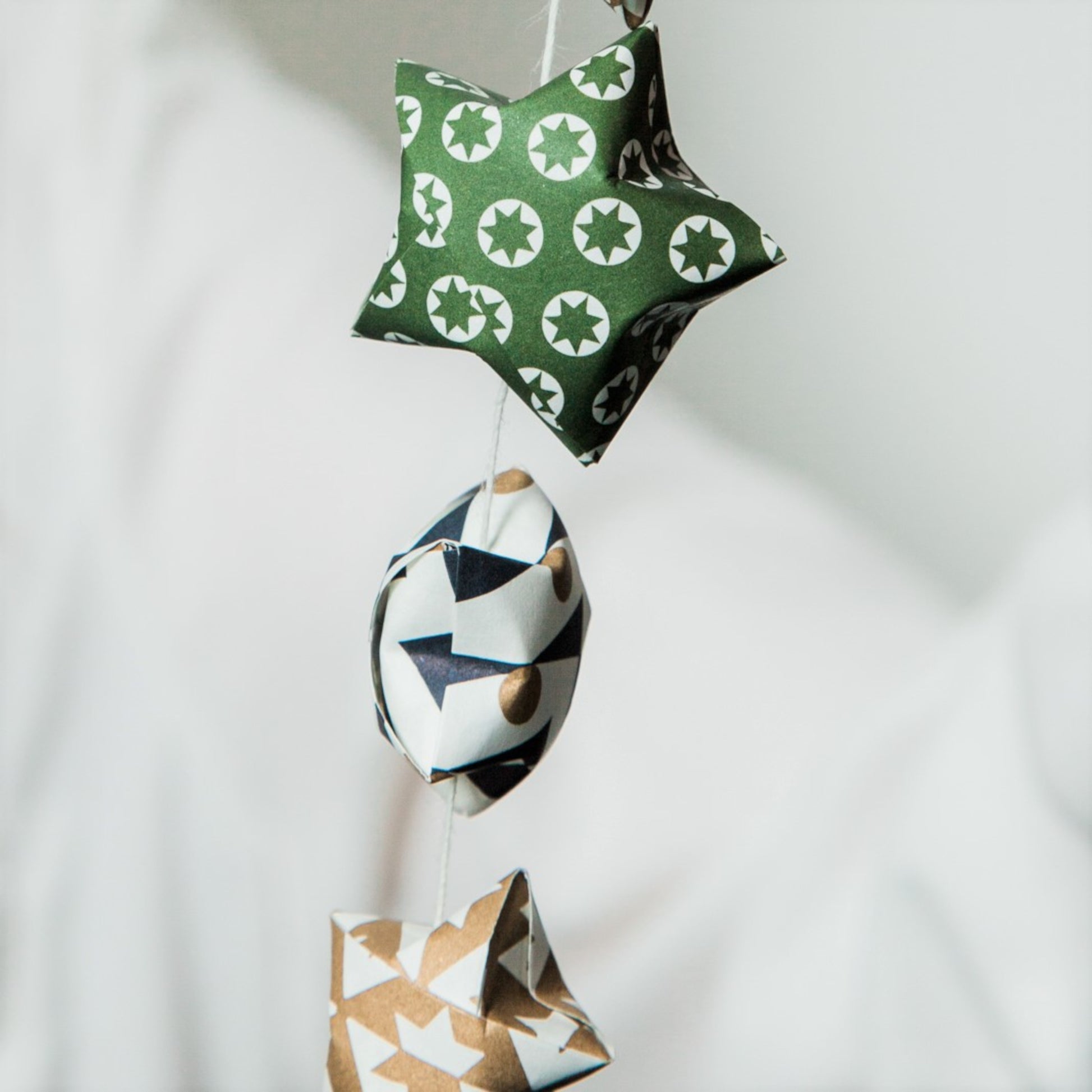 A garland of small paper origami patterned stars "lucky stars" in green, gold and dark blue, close-up