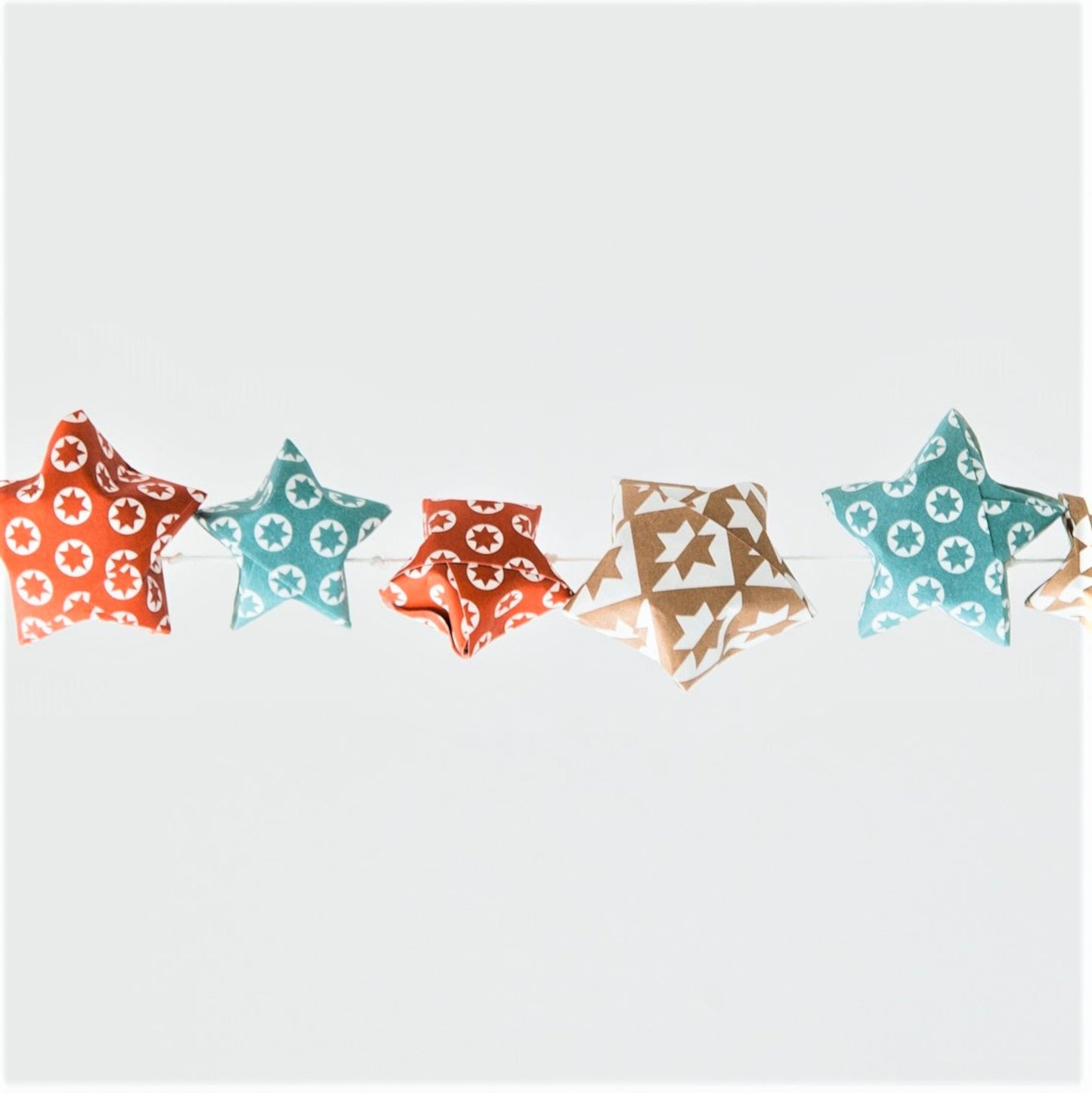 A garland of small paper origami patterned stars "lucky stars" in red, gold and aqua
