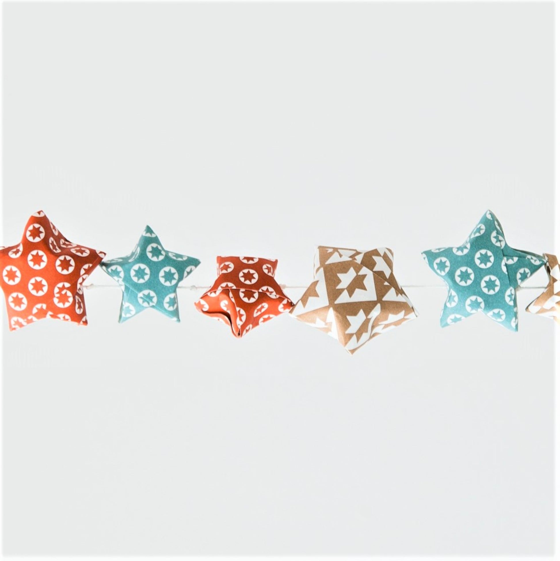 A garland of small paper origami patterned stars "lucky stars" in red, gold and aqua