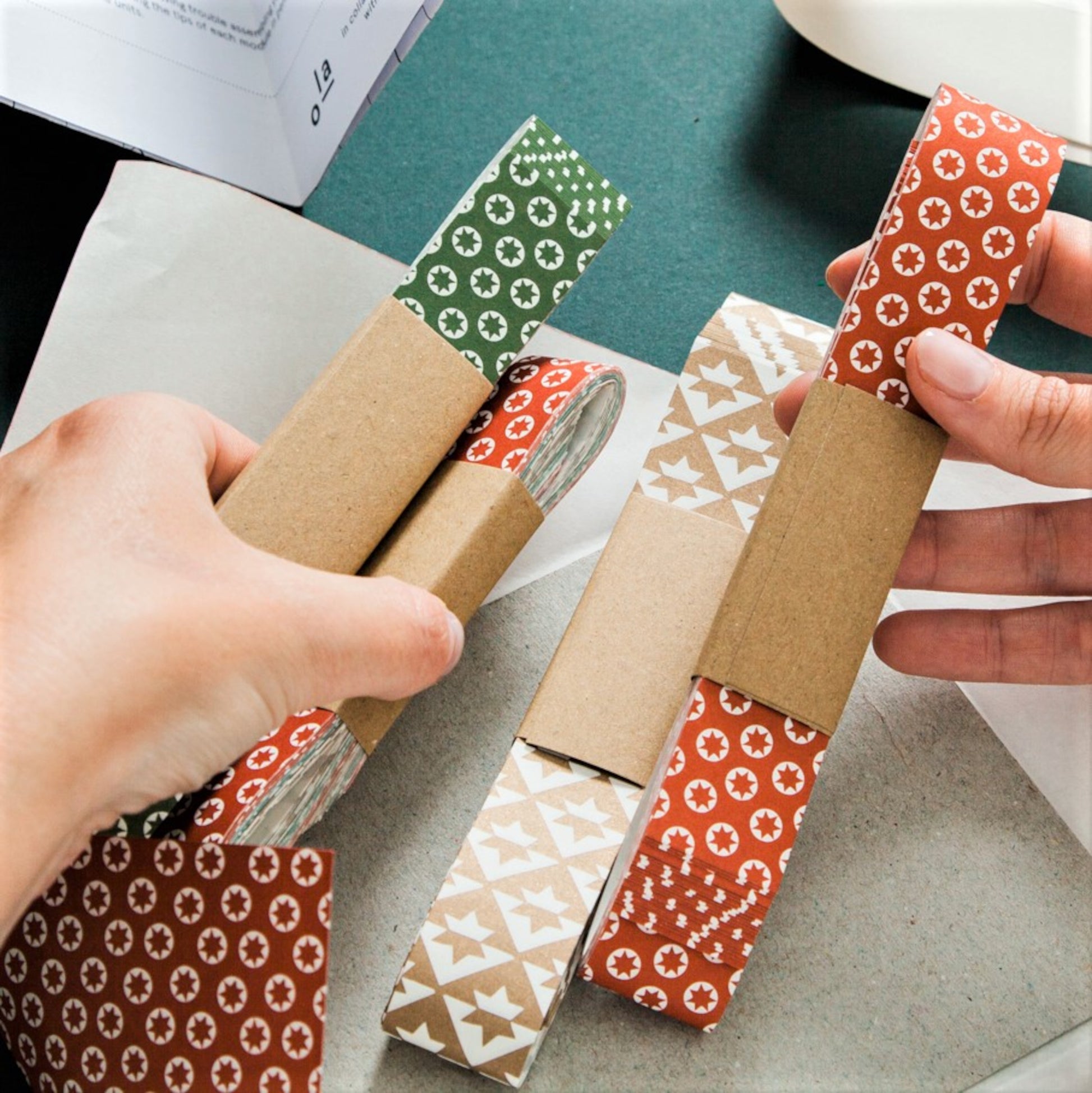 A garland of small paper origami patterned stars "lucky stars" , pictured are the strips of patterned paper used to make the origami stars