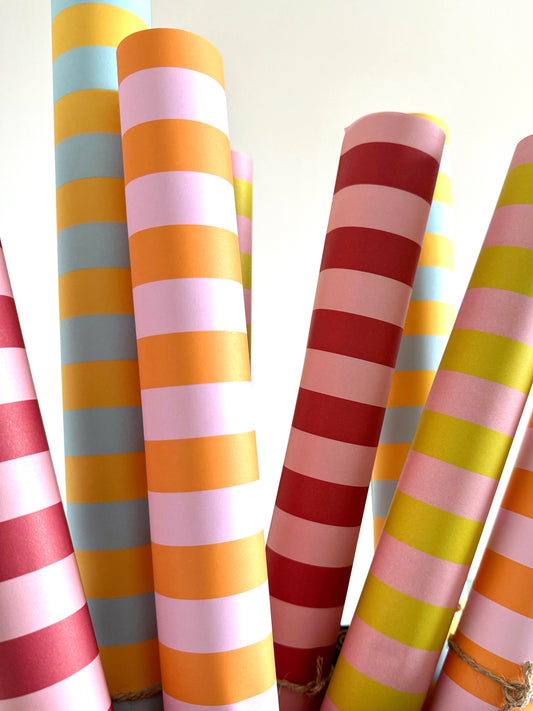 rolls of classic striped wrapping paper in candy colours of pink, orange, aqua and yellow