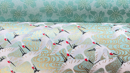 Image of two silkscreen printed Japanese papers - chiyogami - in aqua tones with white cranes and flowers