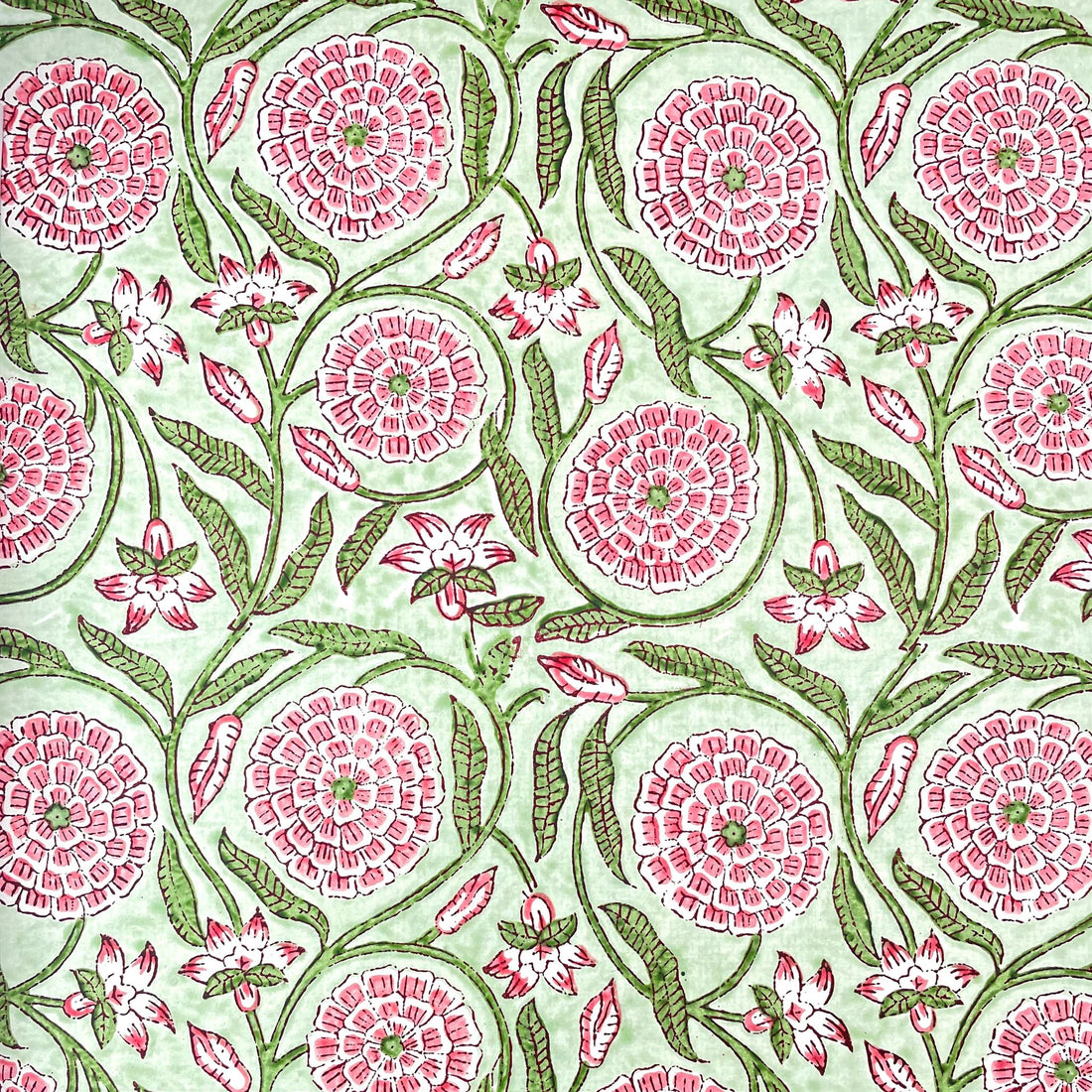 Image of a hand block printed patterned paper with a botanical repeat pattern in pink and green