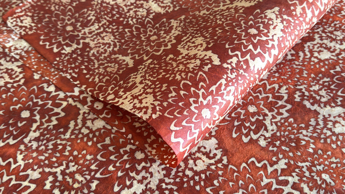 A sheet of batik lokta paper with a floral design in terracotta and cream