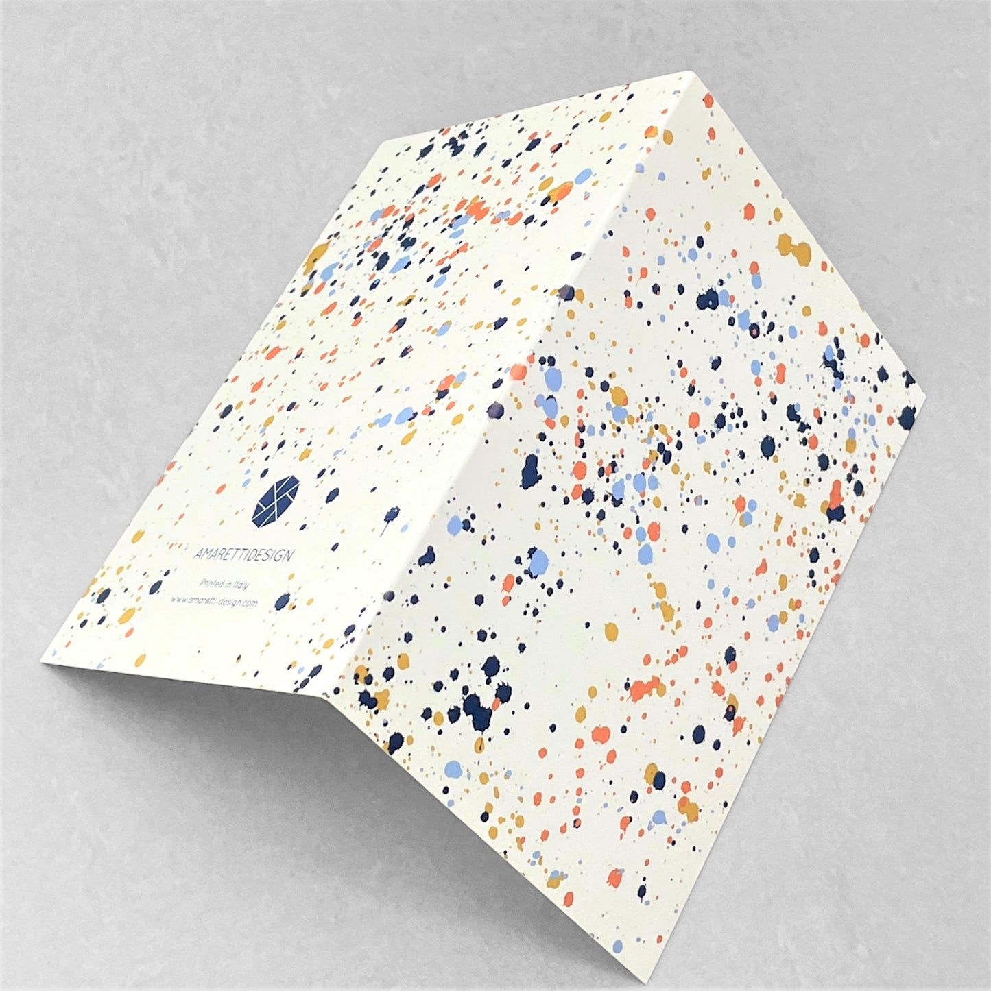 Greetings card with splatter of paint design in navy, pale blue, orange and mustard on ivory paper by amaretti design