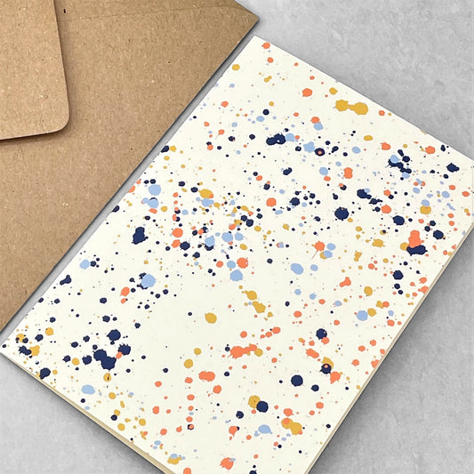 Greetings card with splatter of paint design in navy, pale blue, orange and mustard on ivory paper by amaretti design