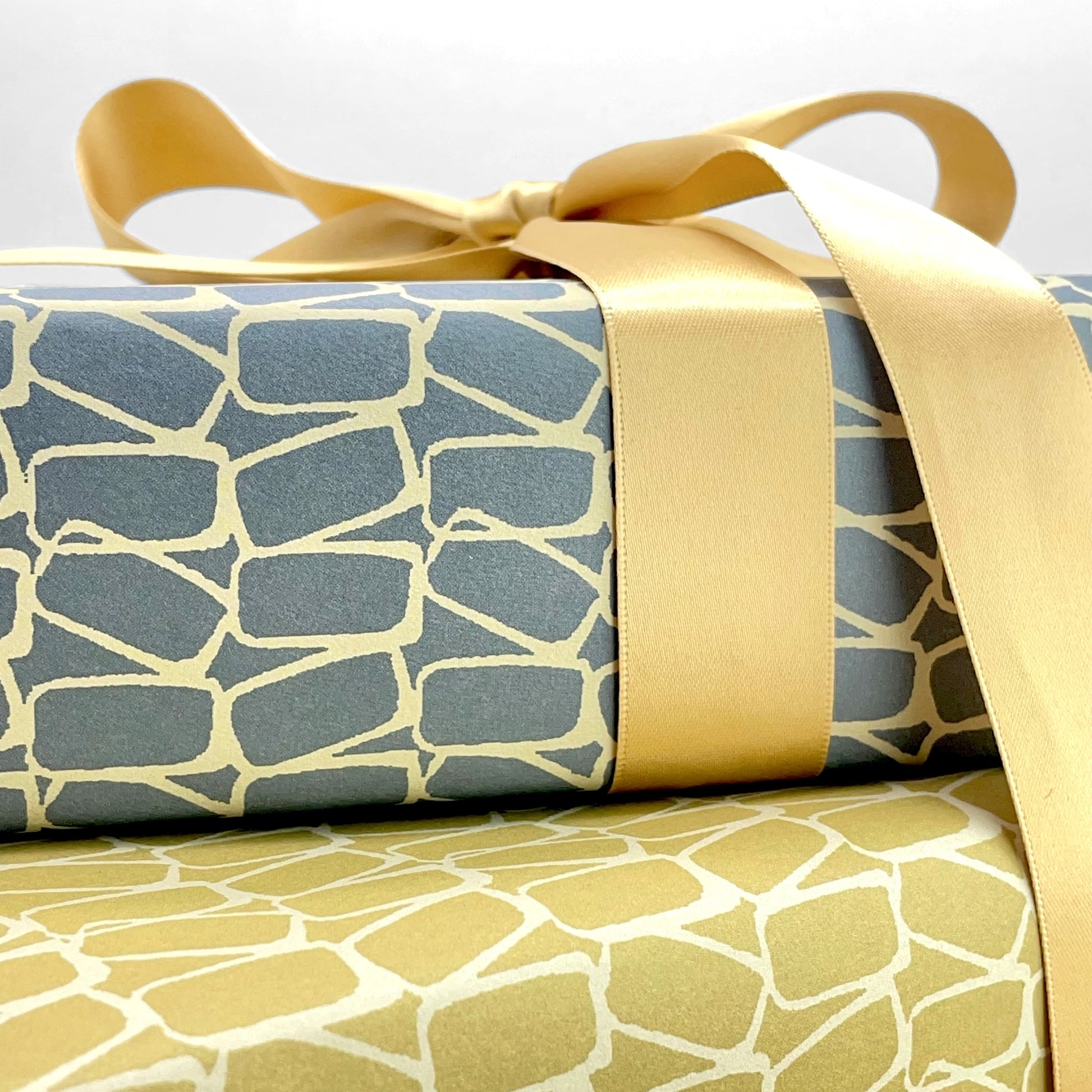 wrapping paper by Anne Davison Studio. Creamy domino outlined shapes on a dusky blue background. Close up 