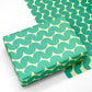 wrapping paper by Anne Davison Studio. Bold green wiggle lines with a retro vibe on beige backdrop.  Pictured as a present