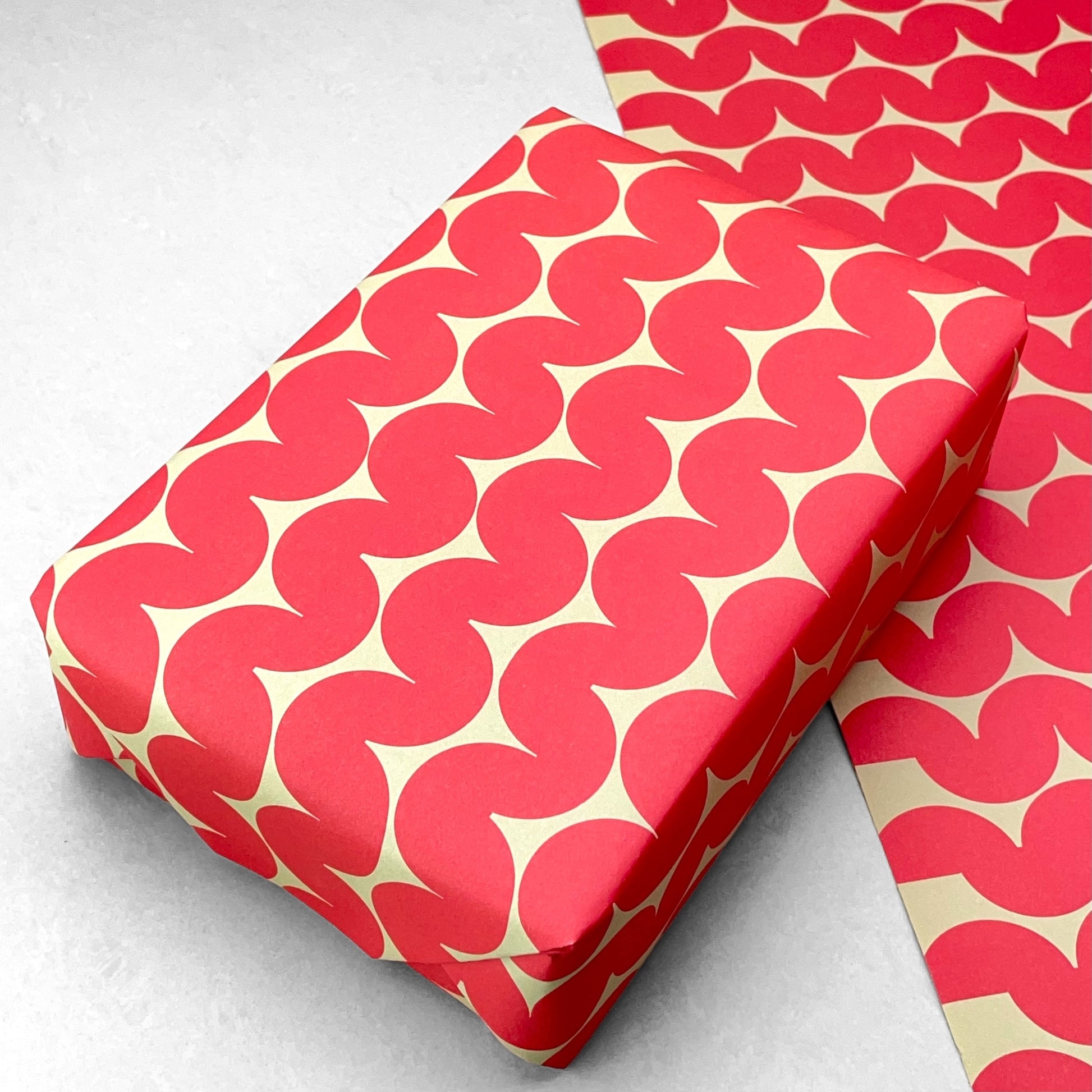 wrapping paper by Anne Davison Studio. Bold red wiggle lines with a retro vibe on beige backdrop.  Shown pictured as a present