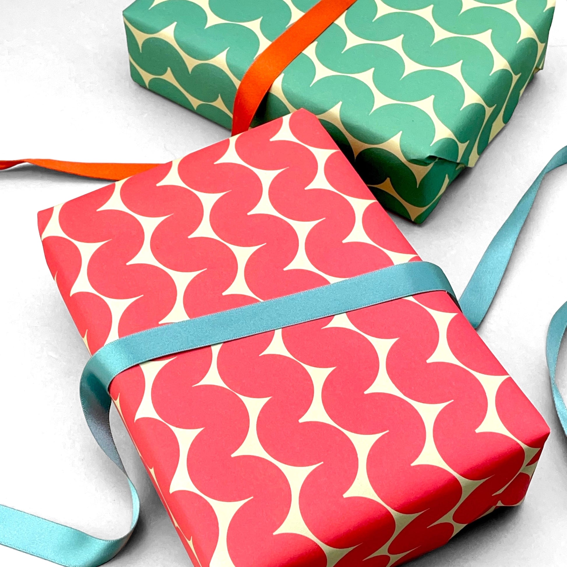 wrapping paper by Anne Davison Studio. Bold red wiggle lines with a retro vibe on beige backdrop.  shown pictured as a present with a blue bow