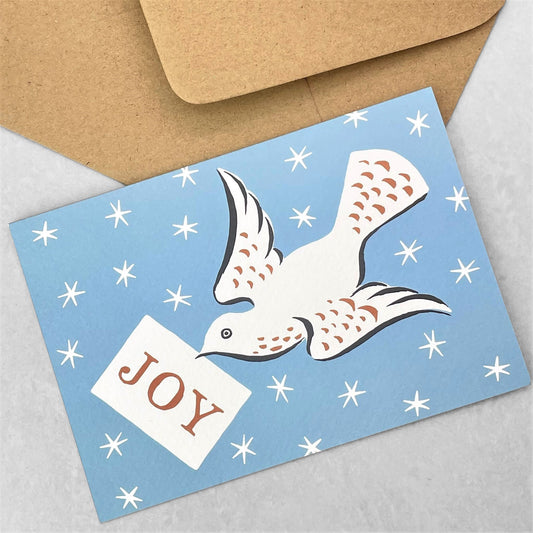 Greetings card of a dove flying in a starry sky with a message of joy, by Ariana Martin