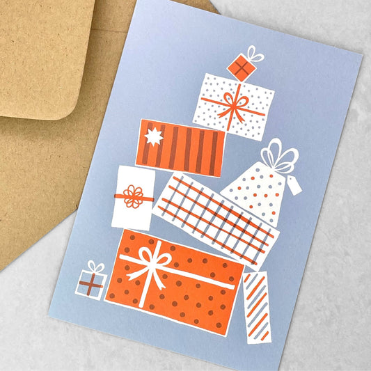 Greetings card of a pile of presents in red and white patterns on a blue backdrop. christmas card by Ariana Martin