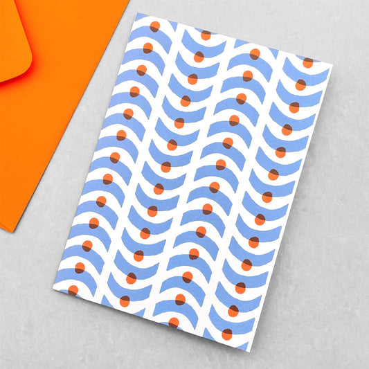 Greetings card with a geometric pattern in blue and orange on a white backdrop. Card by Ariana Martin