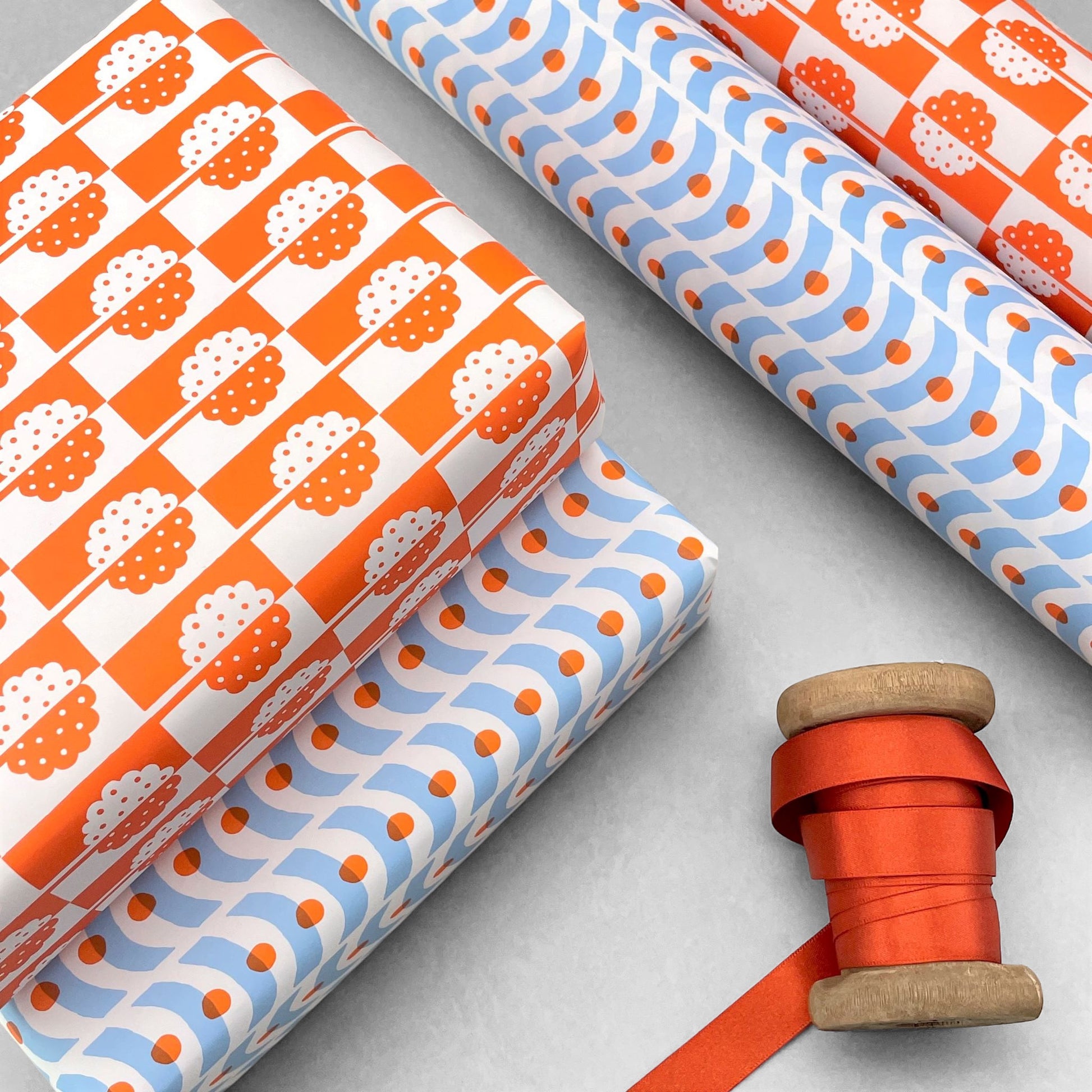 patterned paper, gift wrap, with all-over holly tree design in bright orange and white, by Ariana Martin