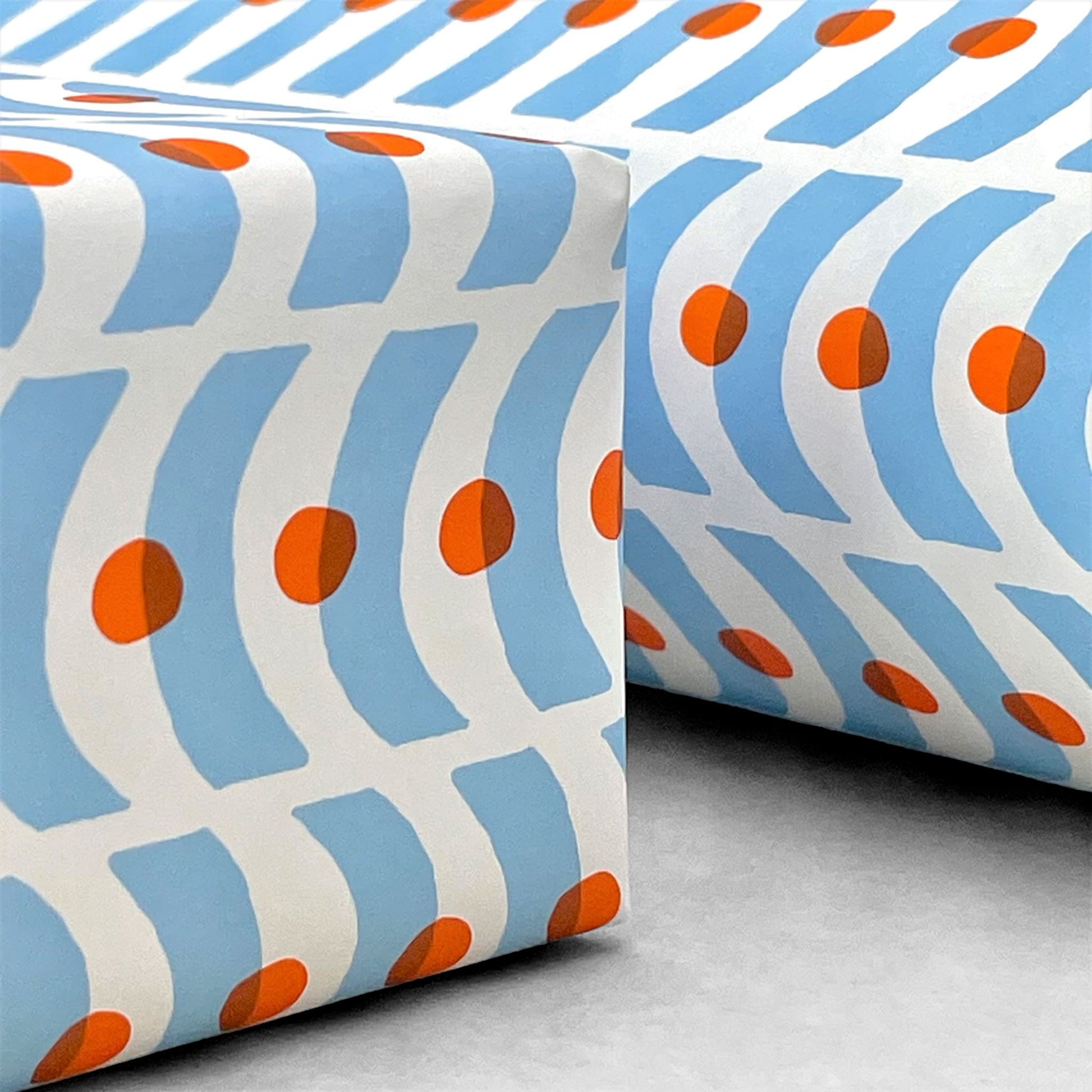 patterned paper, gift wrap with a geometric pale blue wavy pattern and orange dot. By Ariana Martin