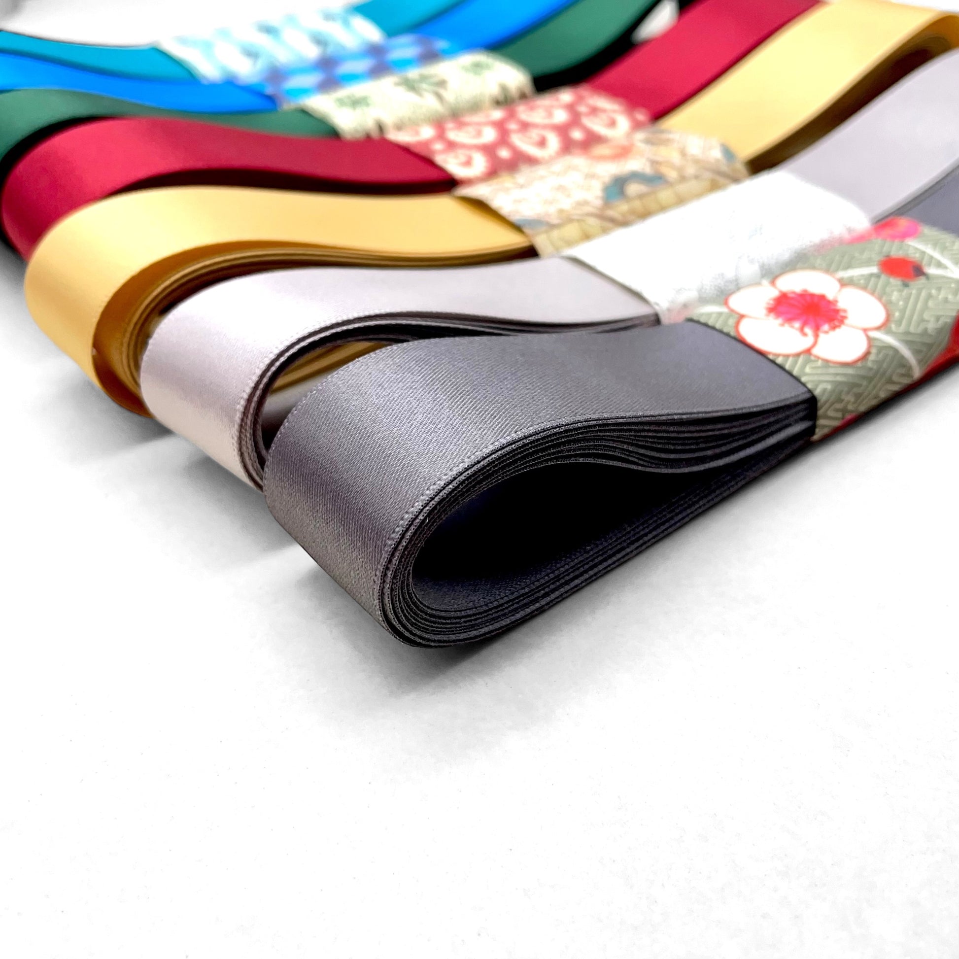 Satin ribbon 25mm wide and 5 metres long, presented with a patterned paper band. colour - smoked grey