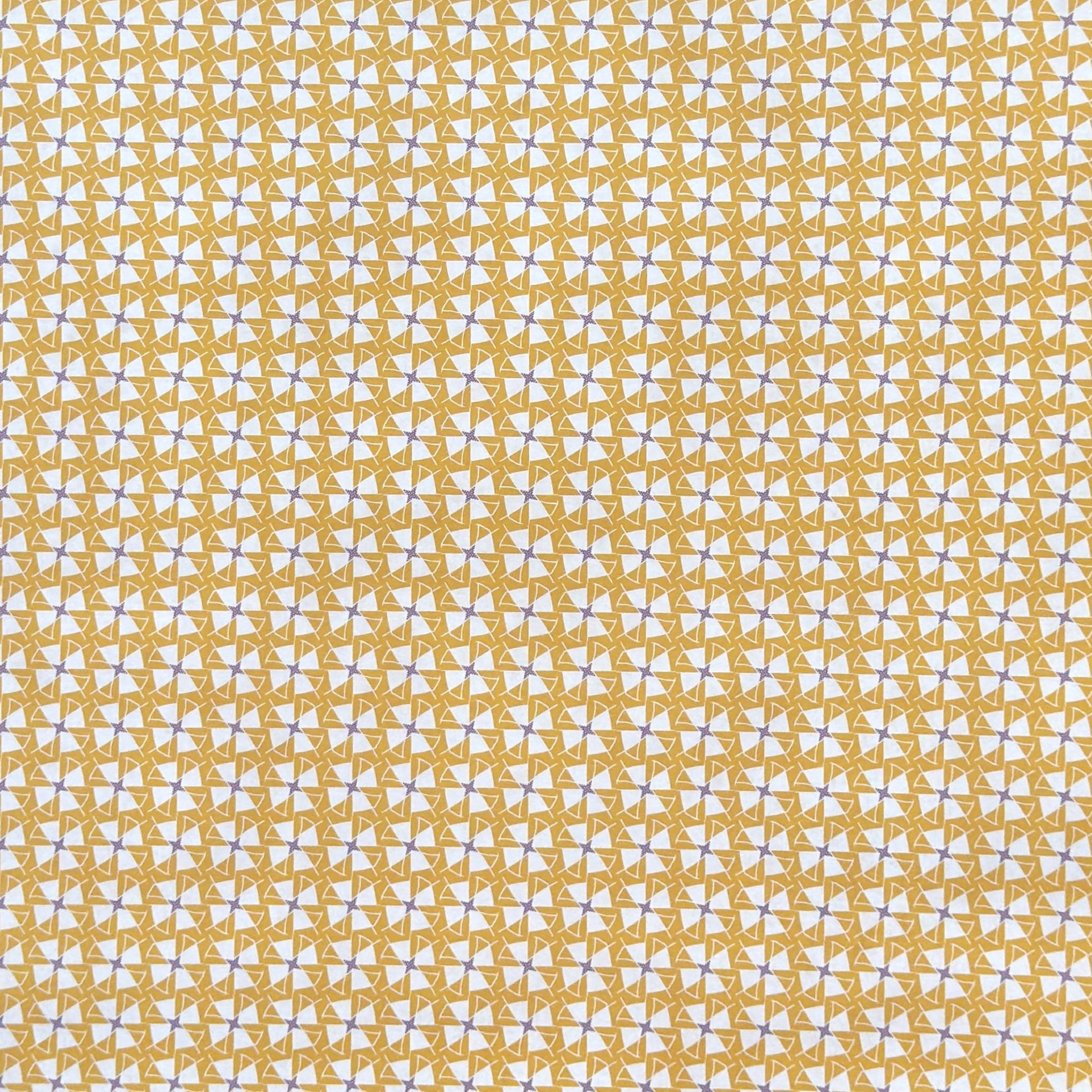 a sheet of wrapping paper with a geometric star pattern in white and purple on mustard yellow background