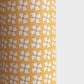 a sheet of wrapping paper with a geometric star pattern in white and purple on mustard yellow background
