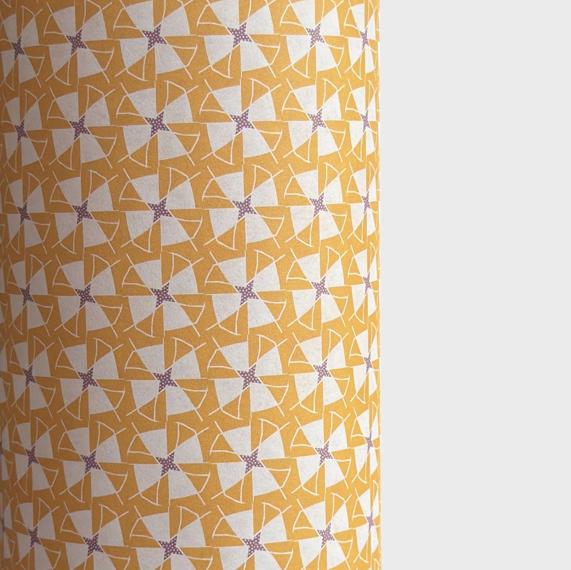 a sheet of wrapping paper with a geometric star pattern in white and purple on mustard yellow background