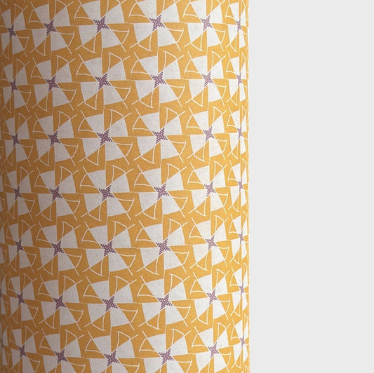 a sheet of wrapping paper with a geometric star pattern in white and purple on mustard yellow background