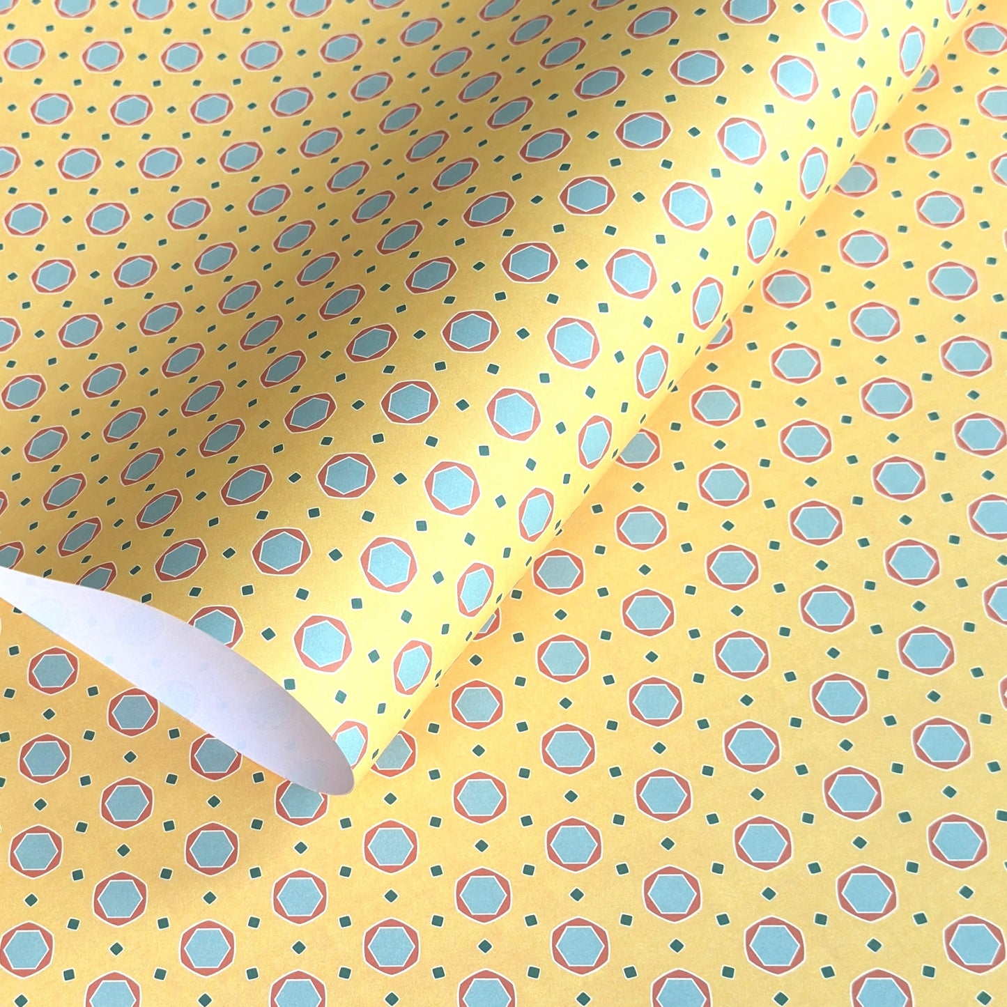 a sheet of wrapping paper with a yellow background and colorful blue circles pattern