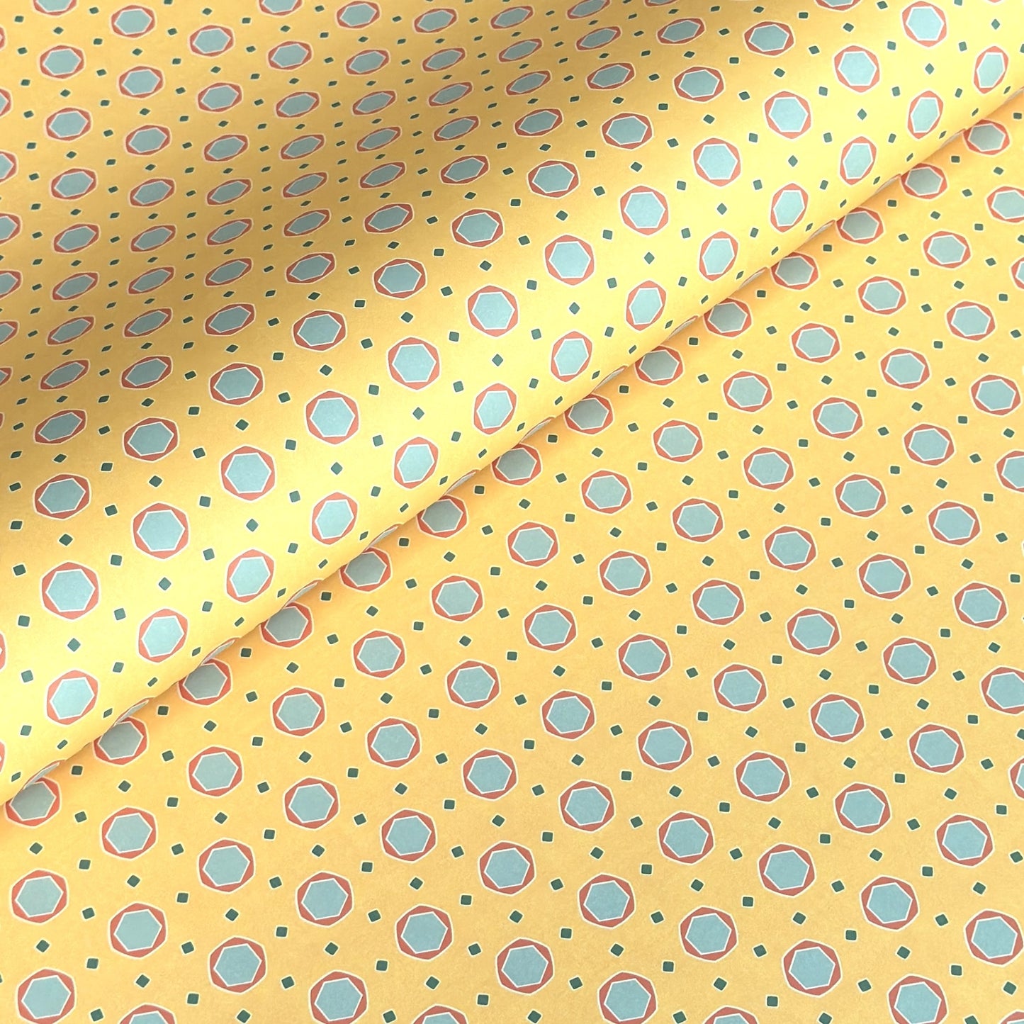 a sheet of wrapping paper with a yellow background and colorful blue circles pattern