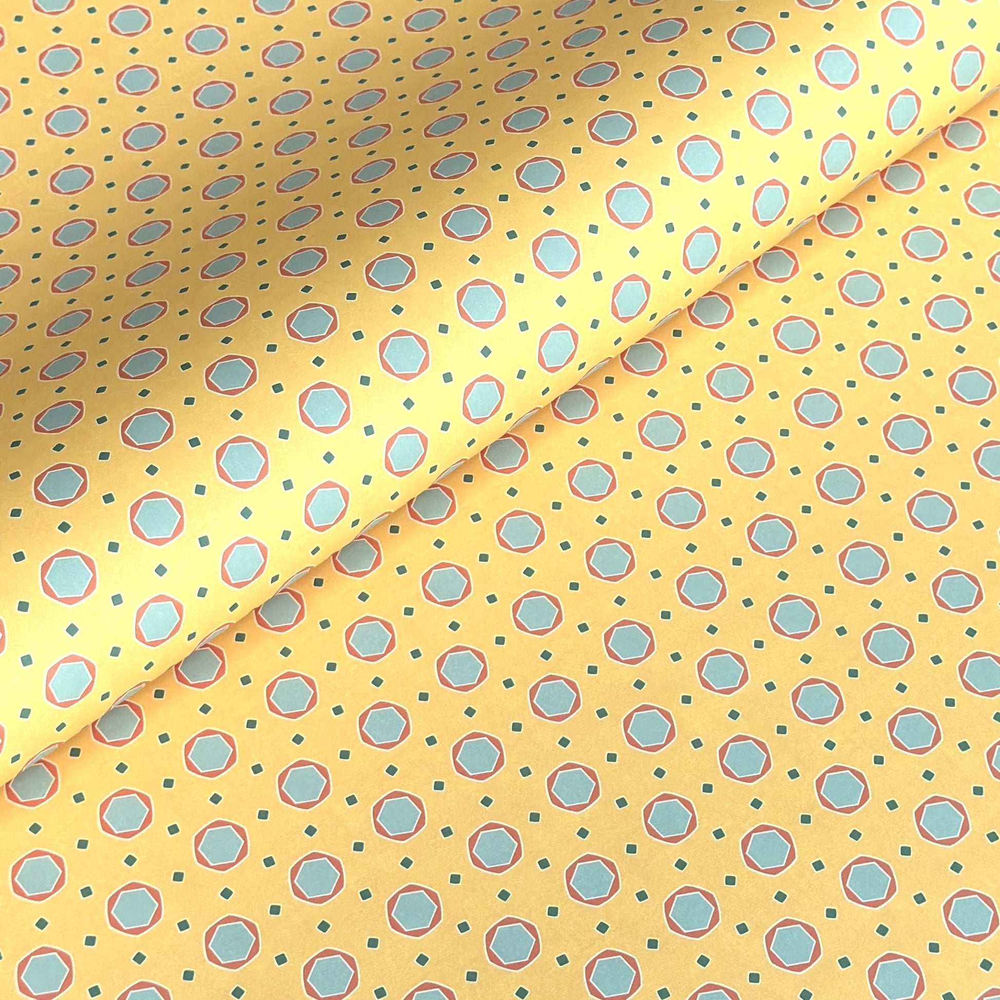 a sheet of wrapping paper with a yellow background and colorful blue circles pattern