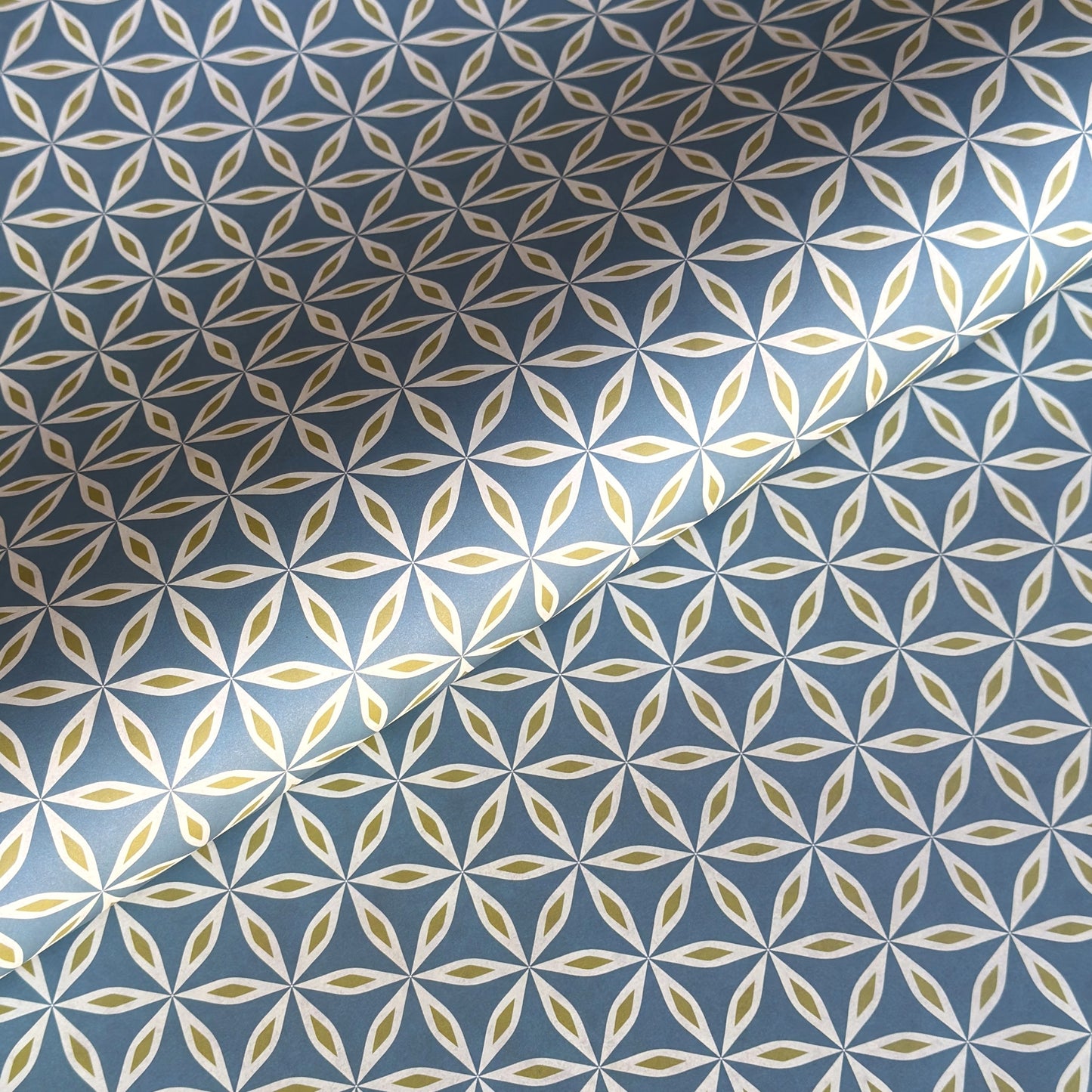 geometric wrapping paper with a star flower pattern in white and lime on teal