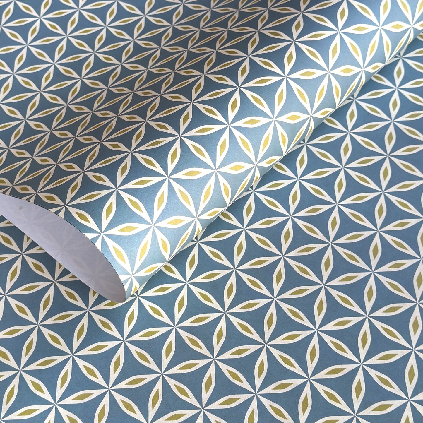 geometric wrapping paper with a star flower pattern in white and lime on teal