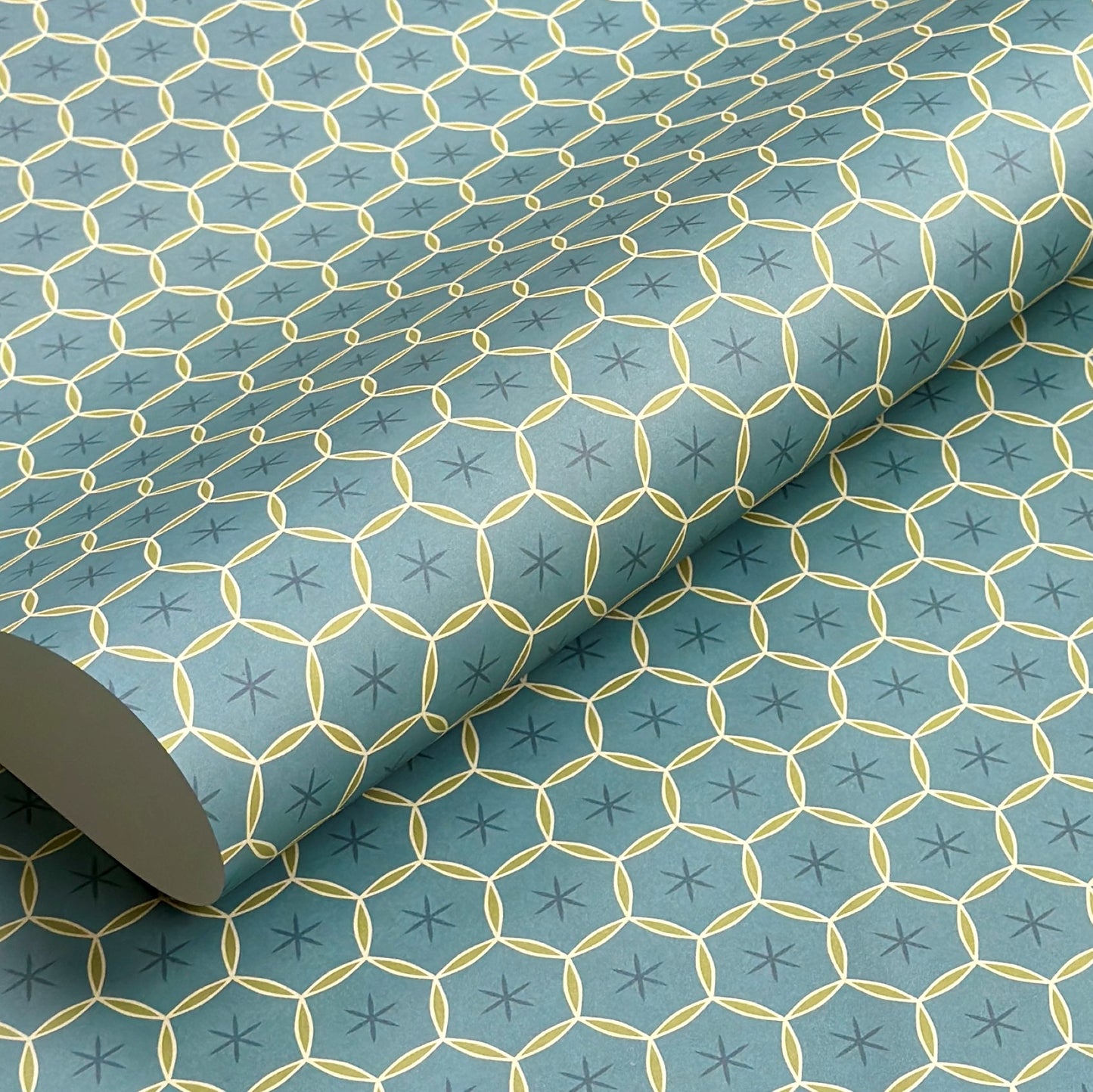 abstract wrapping paper with a geometric circle pattern with a star in the middle in teal blue and lime green