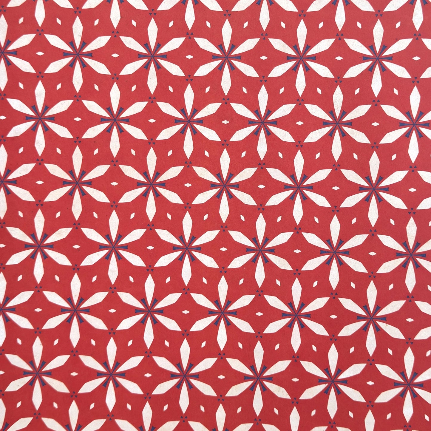 a sheet of wrapping paper with a floral geometric design in white and navy on red
