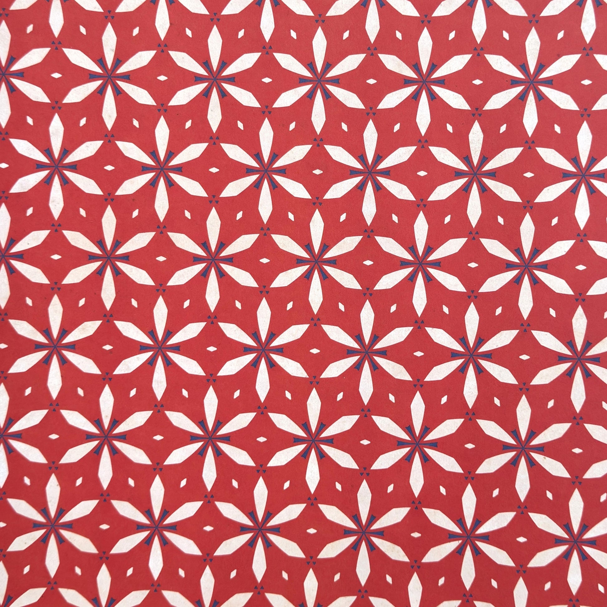 a sheet of wrapping paper with a floral geometric design in white and navy on red