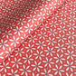a sheet of wrapping paper with a floral geometric design in white and navy on red
