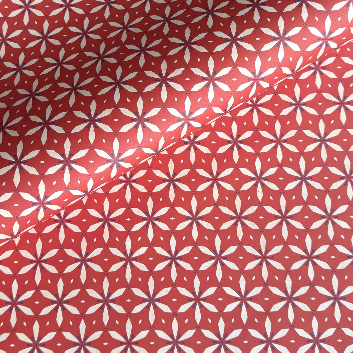 a sheet of wrapping paper with a floral geometric design in white and navy on red