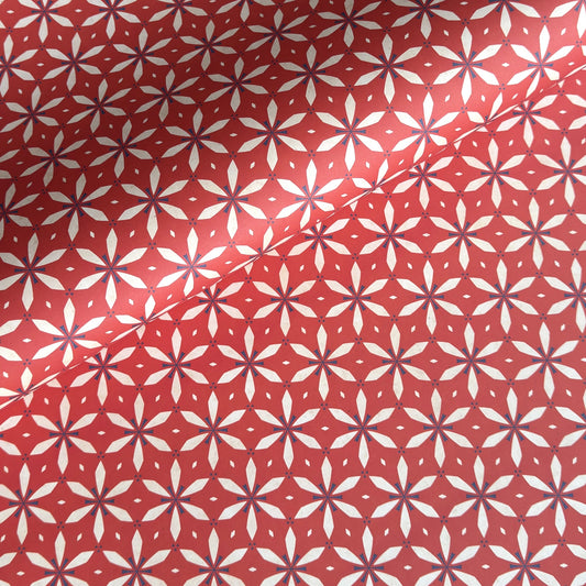 a sheet of wrapping paper with a floral geometric design in white and navy on red
