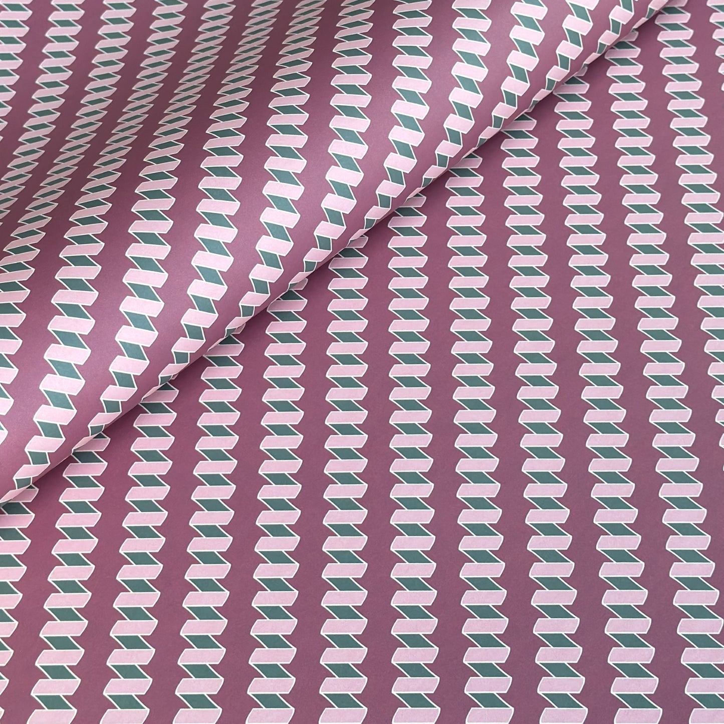 a sheet of wrapping paper with a zigzag pattern in lilac and green on a purple background