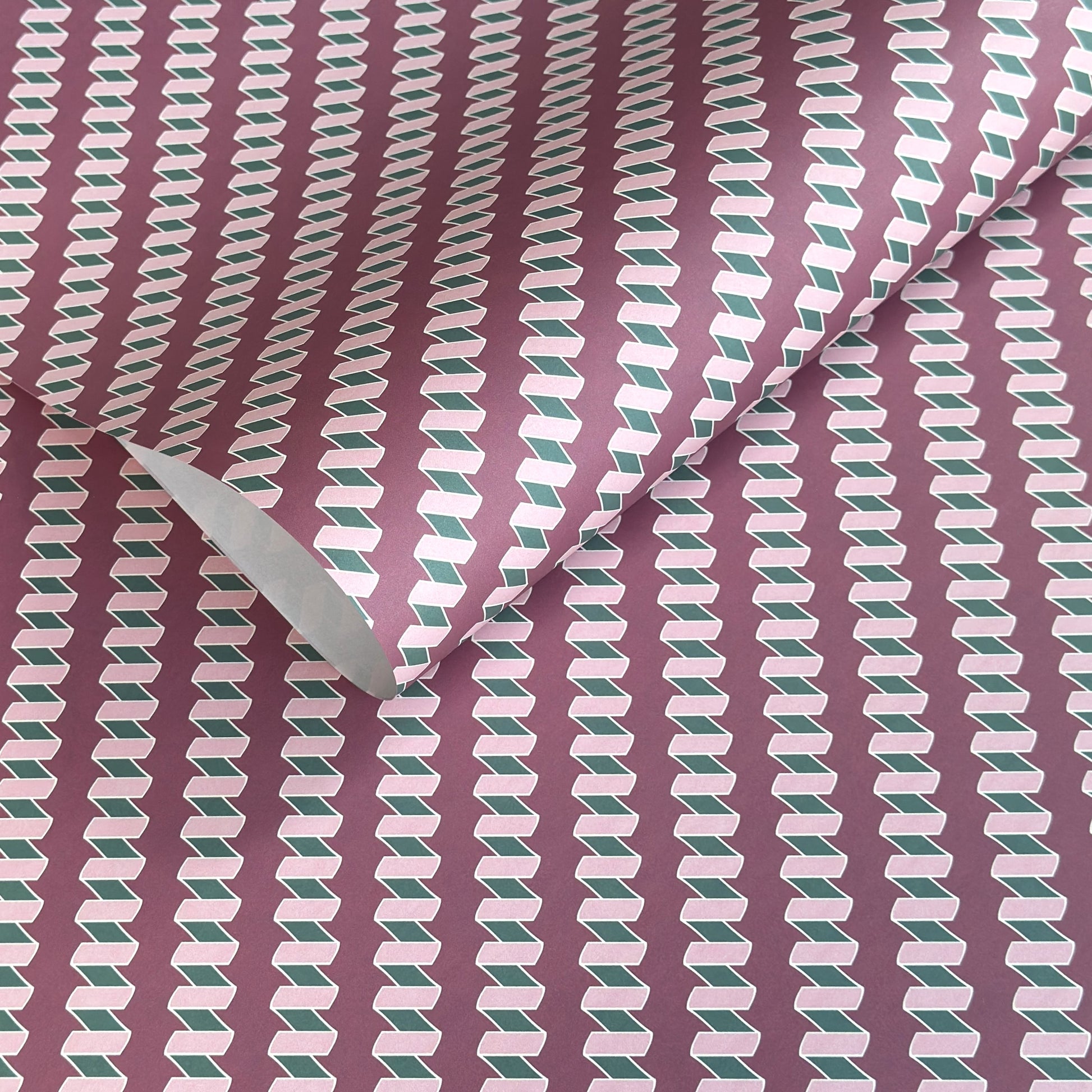 a sheet of wrapping paper with a zigzag pattern in lilac and green on a purple background