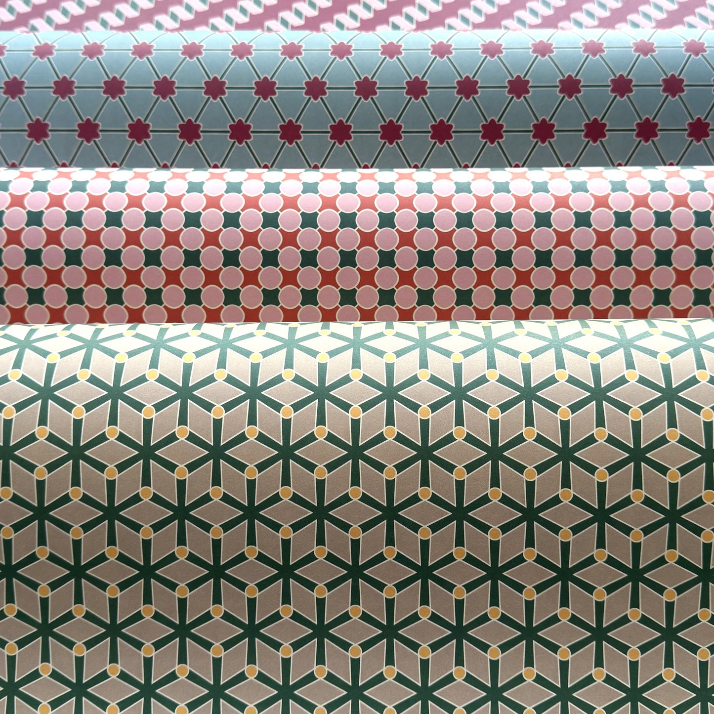 Three rolls of wrapping paper with geometric patterns in different colors.