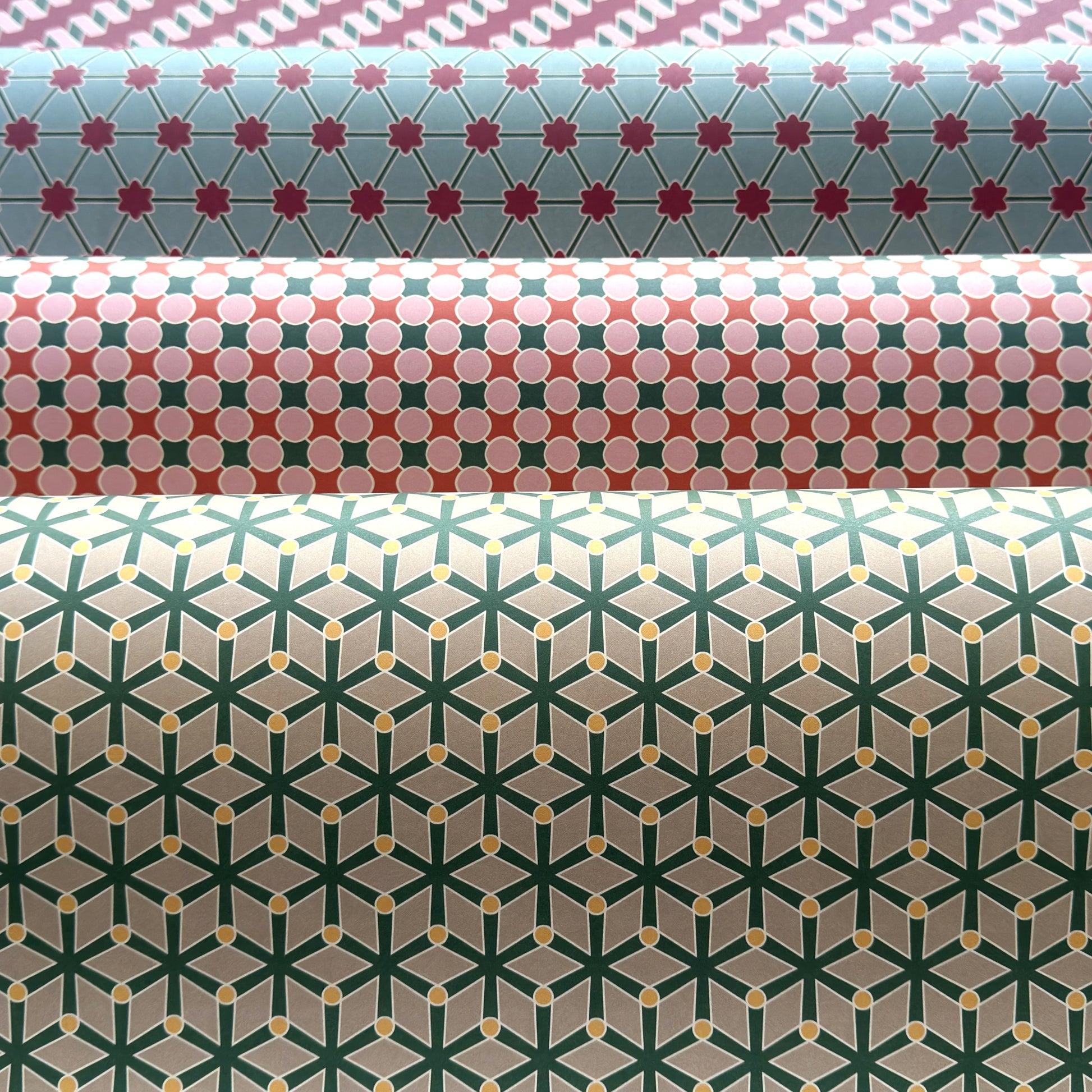Three rolls of wrapping paper with geometric patterns in different colors.