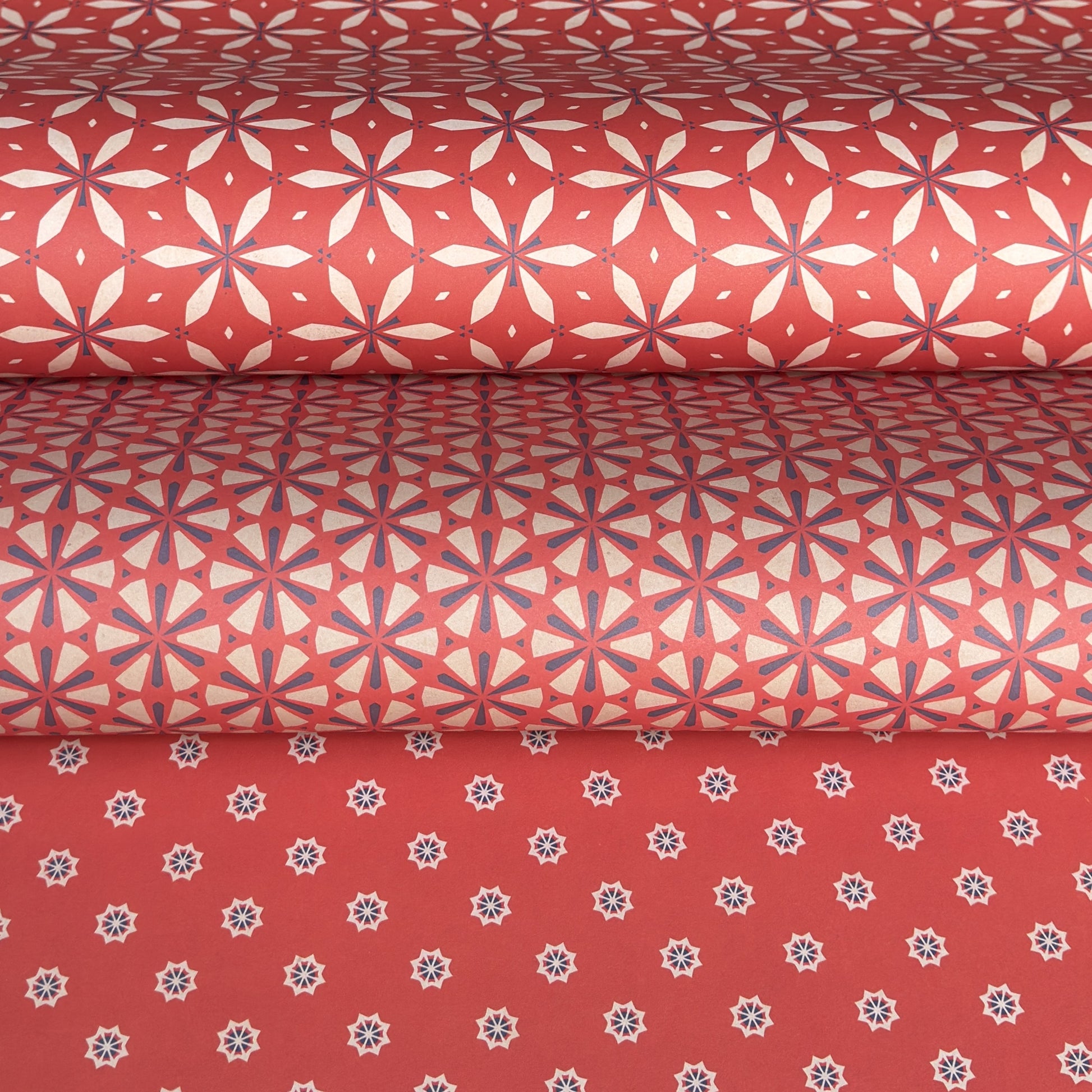 Three rolls of red wrapping paper with geometric patterns