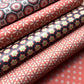 Rolls of patterned paper with geometric designs in red, blue, and white.