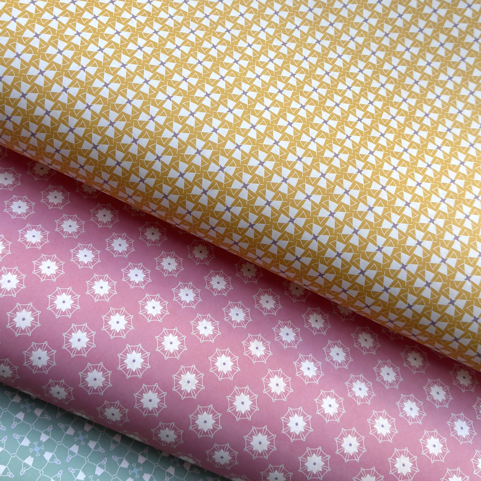 Three sheets of patterned paper in yellow, pink, and green.