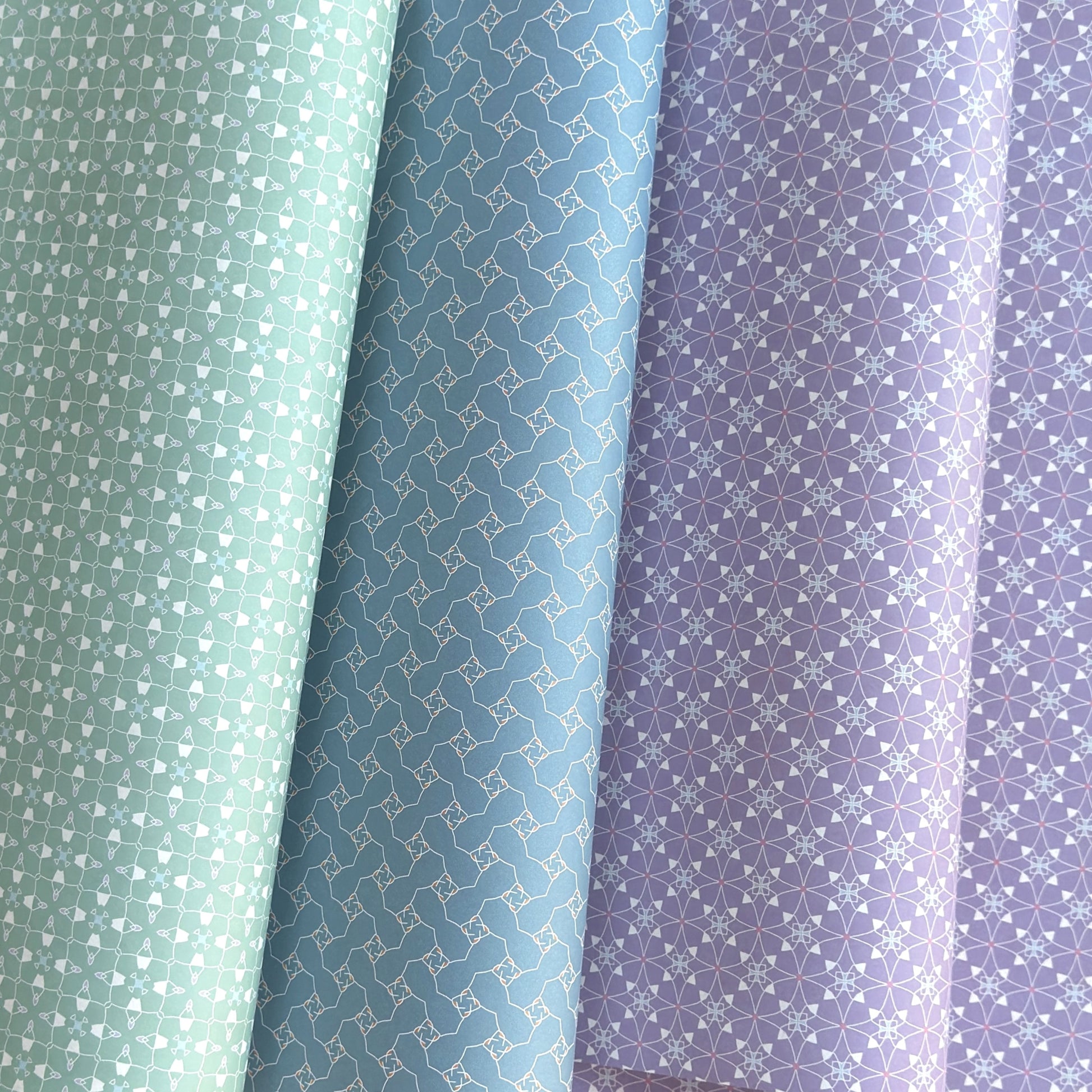 Three wrapping papers with geometric patterns in green, blue, and purple.