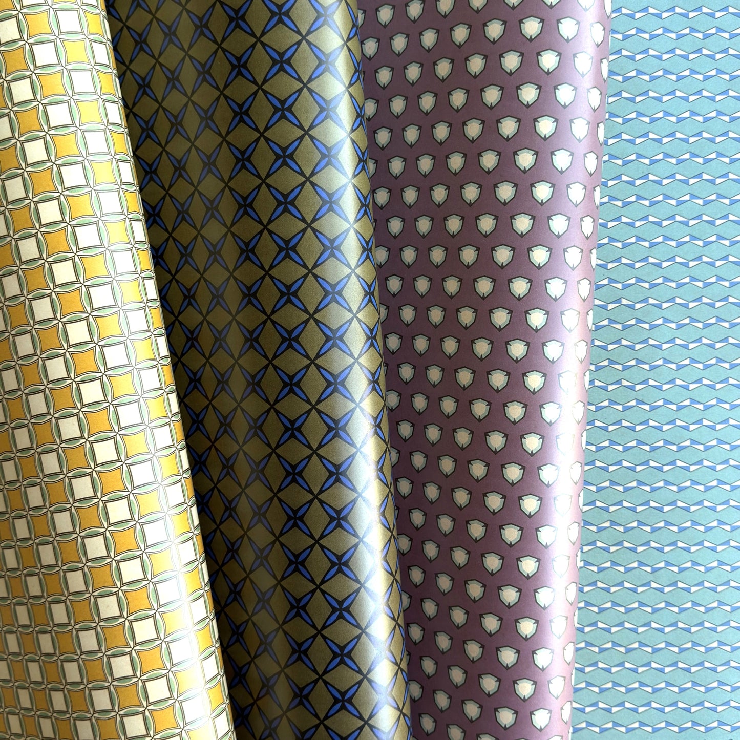 Four rolls of patterned paper with different designs.