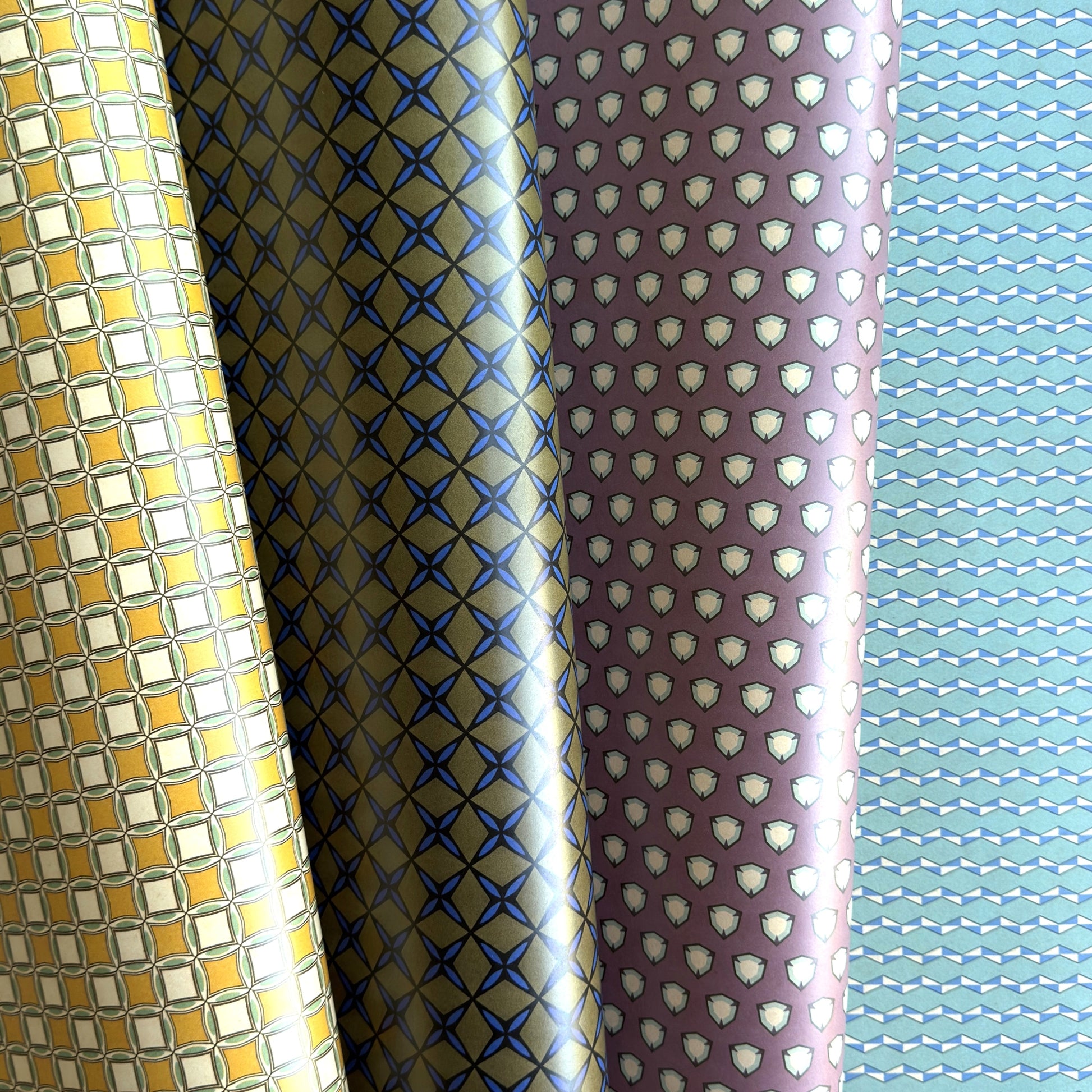 Four rolls of patterned paper with different designs.